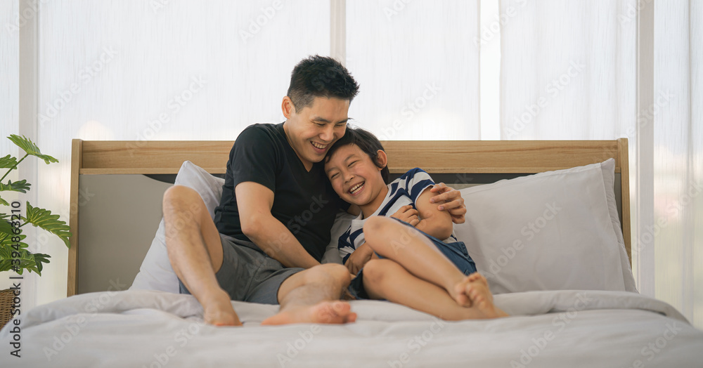 dad and son have good time talking and playing together on bed at home dad and son have good time talking and playing together on bed at home