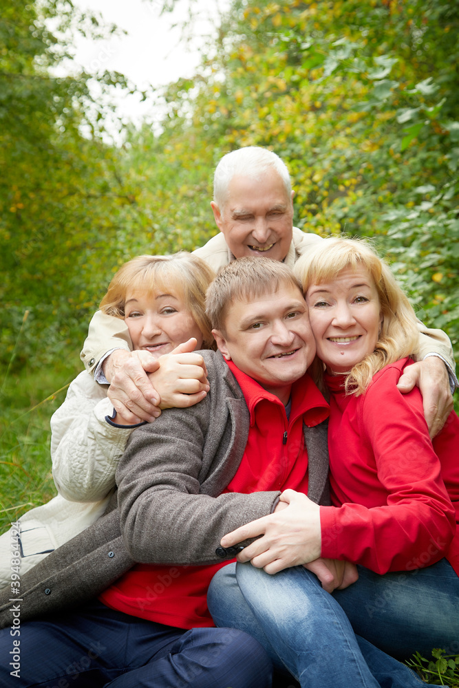 Grandmother and grandfather walking with adult children in nature. Mature couple and young couple walking in the park in an autumn day. Happy family outdoors. Grandmother and grandfather walking with adult children in nature. Mature couple and young couple walking in the park in an autumn day. Happy family outdoors.