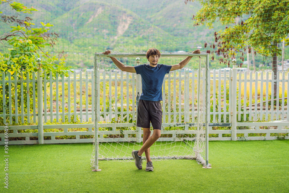 A football trainer for children stands in a children's football goal