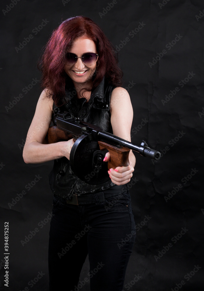 Beautiful woman dressed in black jacket with a gun