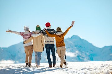 Happy friends embracing against snow capped mountains