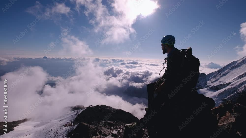 Climber sitting on top of summit after long ascent and enjoying surrounding landscape and sunny weather. Mountains concept. Climber sitting on top of summit after long ascent and enjoying surrounding landscape and sunny weather. Mountains concept.