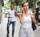 Portrait of young couple walking in city and talking on mobile phones