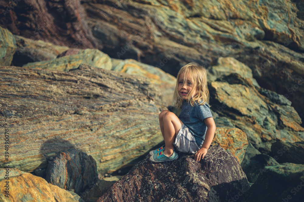 Preschooler sitting on rocks on the beach
