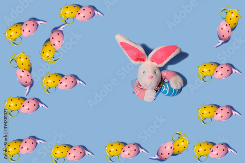 Easter background. Easter eggs pattern. In the center, a rabbit peeks out of torn paper. Horizontal, free space.