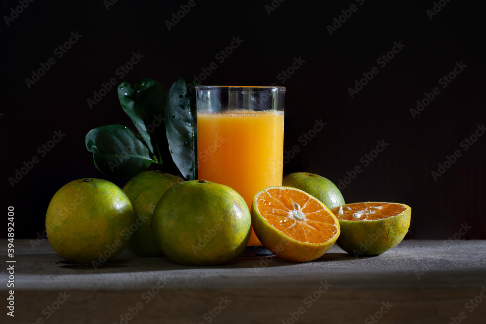 Fototapeta premium Fresh Tangerine and Orange juice in glass on wooden floor