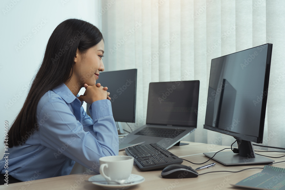 Asian woman software developers sitting in front of computers looking at computer codes on the screen. Asian woman software developers sitting in front of computers looking at computer codes on the screen.