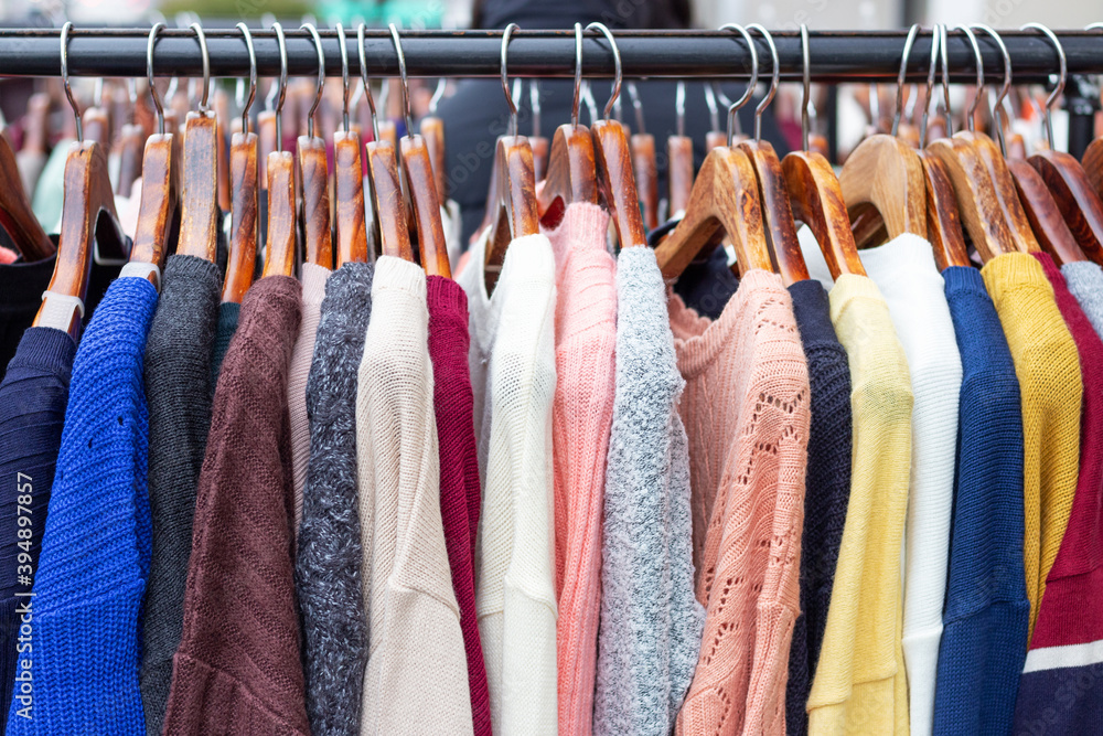 Warm multi-colored sweaters on hangers in a store close-up. Warm multi-colored sweaters on hangers in a store close-up.