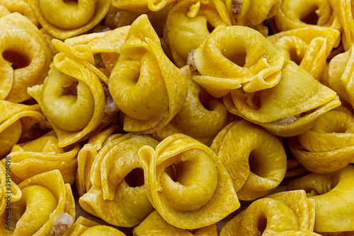 Raw Tortellini in a wooden bowl on wooden table. Traditional italian pasta. Closeup