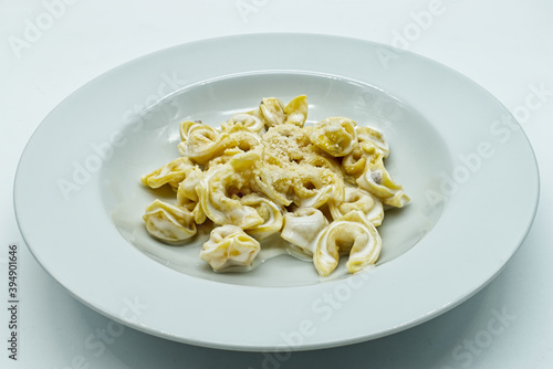 Tortellini alla panna with Parmigiano Reggiano cheese in a white dish. Traditional italian pasta. 