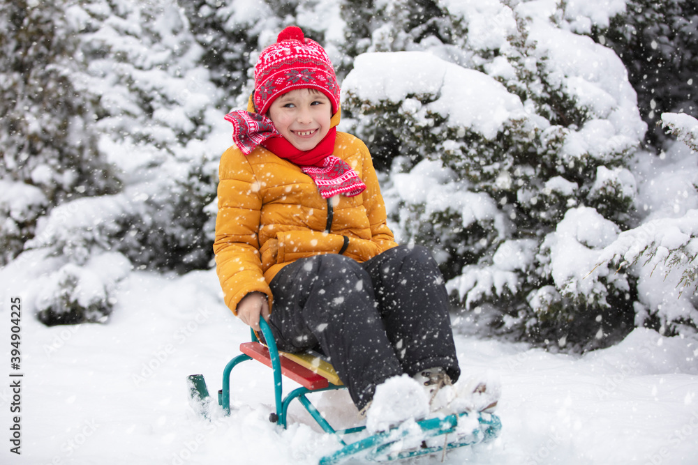 Happy child in winter. A boy in bright clothes sits in a sled in the snow. Happy child in winter. A boy in bright clothes sits in a sled in the snow.