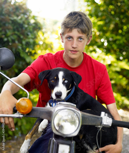 Boy sitting on motorbike and dog perched in front of him photo