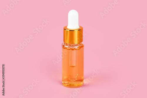 Skin care essence oil dropper glass bottle on pink background. Hydrating serum, vitamins for face skin. Anti aging serum with collagen and peptides in glass bottle with dropper. Aesthetic, minimalism.
