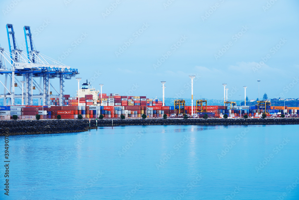 Containers stacked on wharf next to cranes ready for loading on cargo ships - taken from the water Containers stacked on wharf next to cranes ready for loading on cargo ships - taken from the water