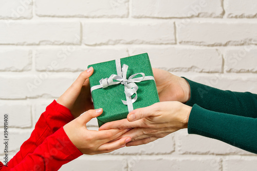Fotografie Female hands holding a small gift box wrapped in packing paper