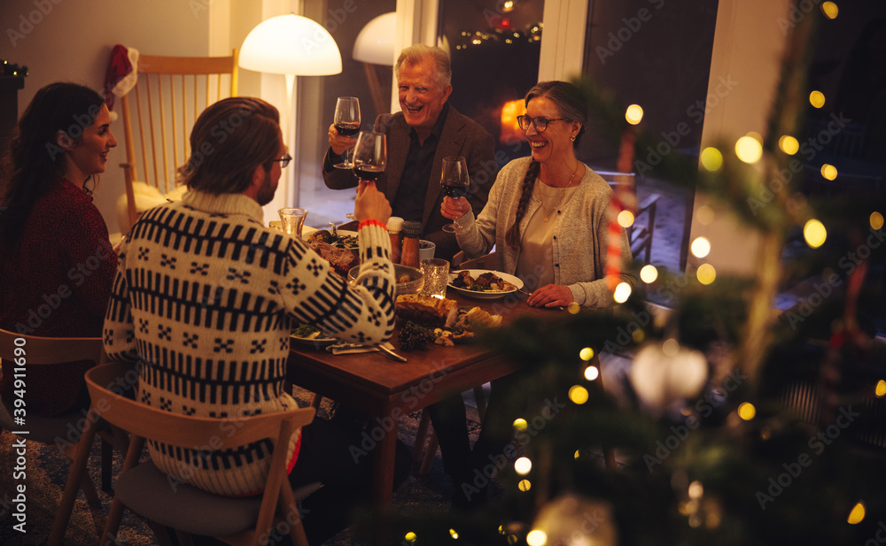 Family enjoying Christmas dinner with drinks - obrazy, fototapety, plakaty 