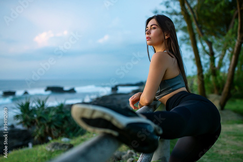 A young woman is engaged in stretching her legs by the sea.