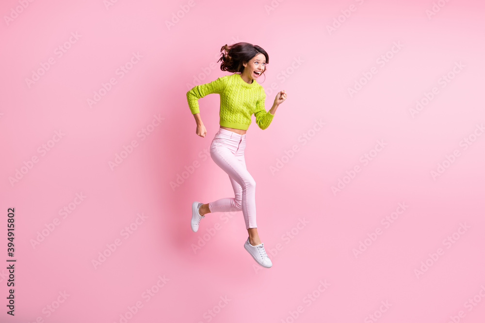 Full length photo of adorable sweet wavy lady wear green sweater jumping running fast isolated pastel pink color background