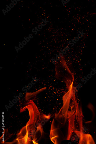 Fiery flame with sparks on a black background. Texture (element) for barbecue or cooking.