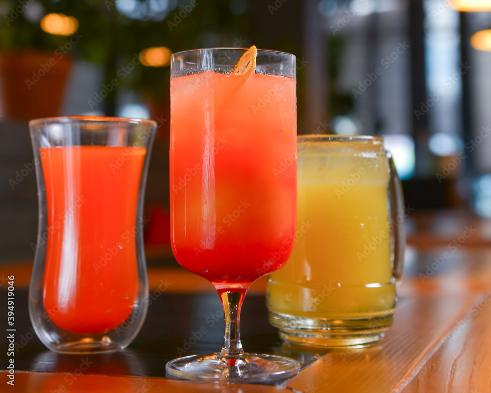 Three cocktails drinks on wooden table at bar indoors. Delicious fruit drinks for refreshment. Alcohol beverage.