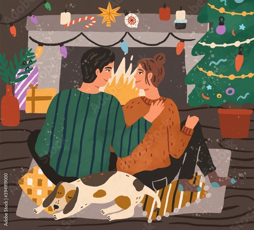 Young couple enjoying Christmas time together by fireplace at home decorated ...