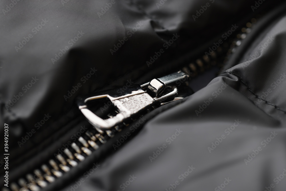 Steel jogging legs on open zipper black jacket close-up. Clothing repair concept Steel jogging legs on open zipper black jacket close-up. Clothing repair concept