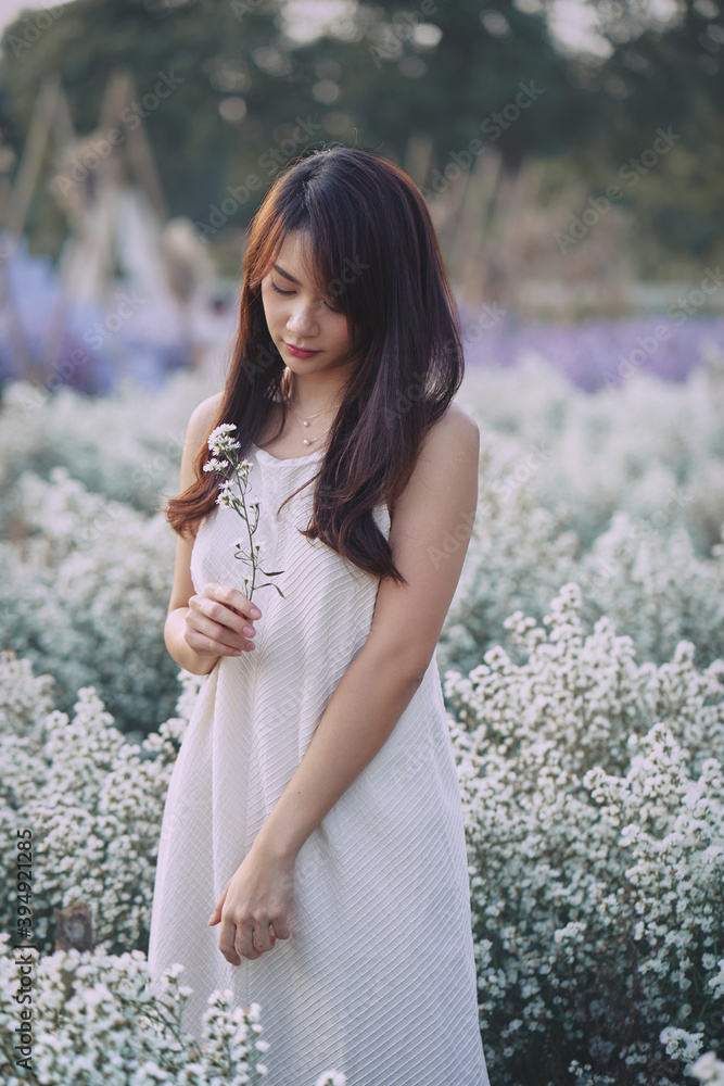 Happy Asian woman wear white dress walking in white cutter flowers garden