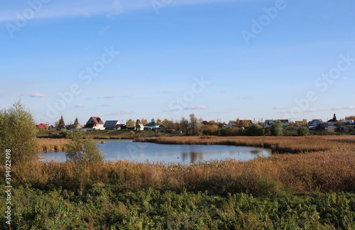 lake with a reservoir near the houses in the village in autumn rural landscape in nature