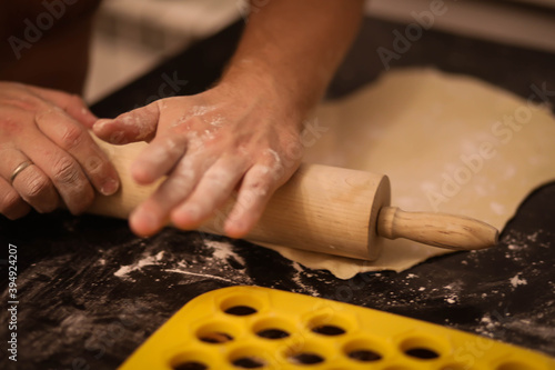 cook rolls out the dough, men's hands work with the dough, cooking dough for dumplings, cook's hands in flour