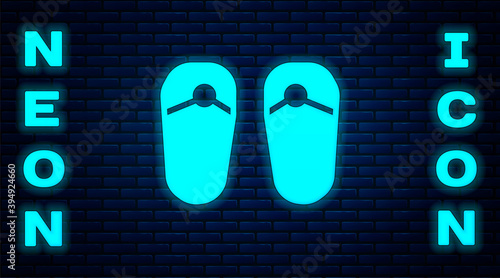 Glowing neon Flip flops icon isolated on brick wall background. Beach slippers sign. Vector.