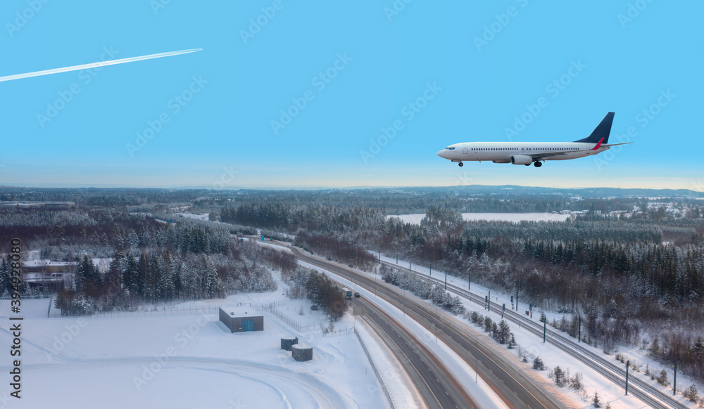 A passenger plane landing at Oslo Gardermoen International Airport - Airport in a snow covered - Beautiful winter landscape with aerial view of highway road and snow-covered road