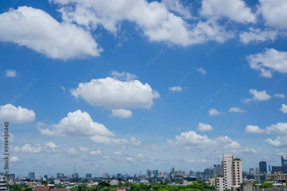 Beautiful white fluffy clouds on vivid blue sky in a suny day above a big city, part of Bangkok in Thailand