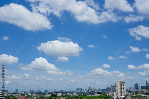 Beautiful white fluffy clouds on vivid blue sky in a suny day above a big city, part of Bangkok in Thailand