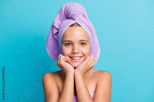 Photo portrait of small girl in bathroom wearing turban with silky soft skin touching cheeks isolated on vivid blue color background