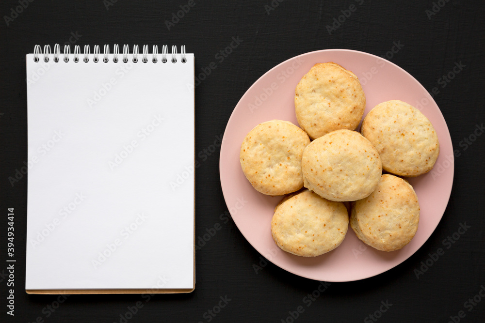 Homemade Flaky Buttermilk Biscuits on a pink plate, blank notepad on a black surface, top view. Flat lay, overhead, from above. Copy space. Homemade Flaky Buttermilk Biscuits on a pink plate, blank notepad on a black surface, top view. Flat lay, overhead, from above. Copy space.