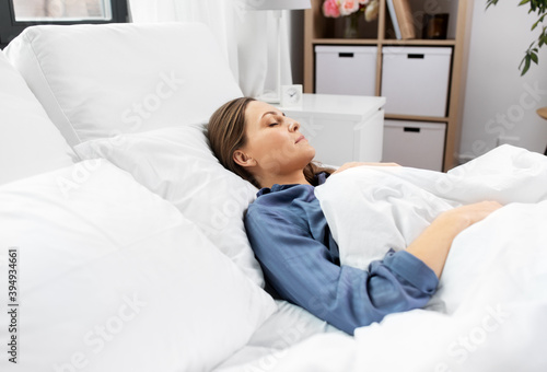 people, relax and comfort concept - young woman sleeping in bed at home