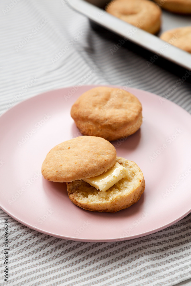 Homemade Flaky Buttermilk Biscuit on a pink plate on cloth, low angle view. Close-up. Homemade Flaky Buttermilk Biscuit on a pink plate on cloth, low angle view. Close-up.