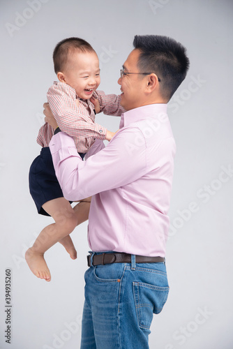 Asian dad hold his toddler son on his chest