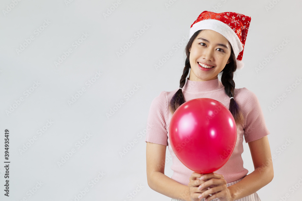 Portrait of young asia woman wearing a santa hat. Holding a balloon and smiling. On white background Portrait of young asia woman wearing a santa hat. Holding a balloon and smiling. On white background