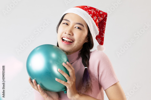 Portrait of young asia woman wearing a santa hat. Holding a balloon and smiling. On white blackground © CREATIVE WONDER