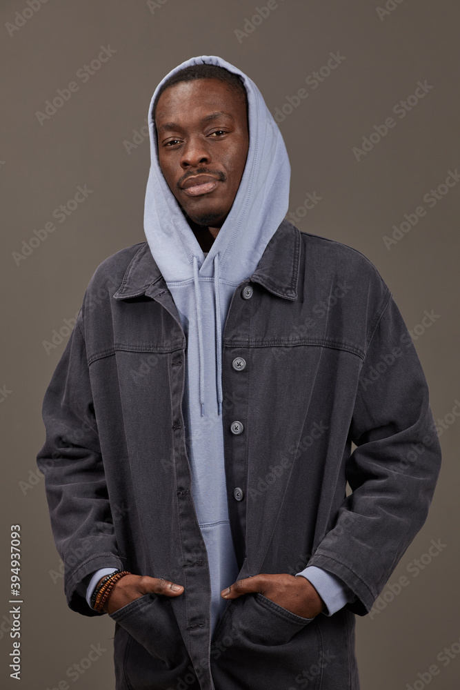 Portrait of African man in hoody and in jeans jacket posing at camera isolated on grey background