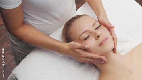 Young, beautiful and healthy woman in massaging salon. Traditional face massage therapy and skin care.