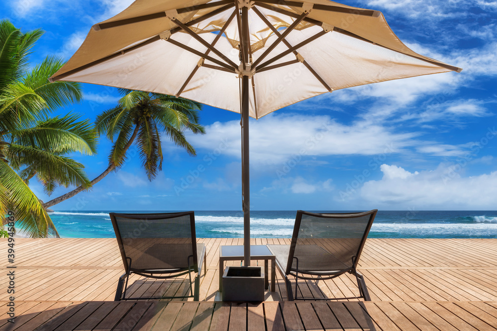 Tropical Sunny beach with umbrella and deckchairs on wooden floor, palm trees and the turquoise sea on Paradise island. Tropical Sunny beach with umbrella and deckchairs on wooden floor, palm trees and the turquoise sea on Paradise island.