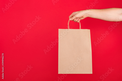 Close up photo of men holding craft paper bag isolated on red background