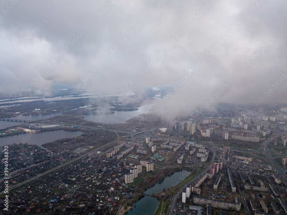 High aerial flight in the clouds over Kiev. An autumn cloudy morning, the Dnieper River is visible on the horizon.