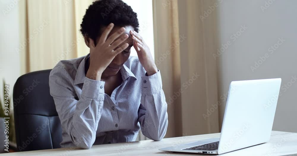 Sad tired African woman working laptop at office. Unhappy female person use computer technology at home. Worried mixed race girl feels stress at freelance work. Upset business lady looking at screen Sad tired African woman working laptop at office. Unhappy female person use computer technology at home. Worried mixed race girl feels stress at freelance work. Upset business lady looking at screen