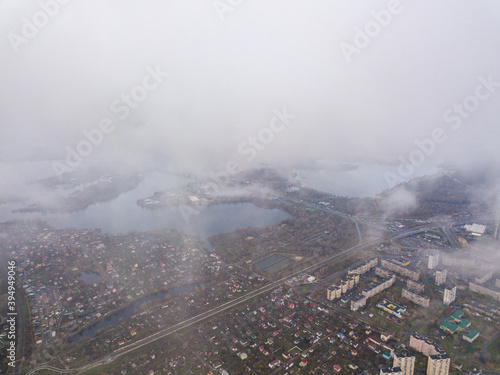 High aerial flight in the clouds over Kiev. An autumn cloudy morning, the Dnieper River is visible on the horizon. © Sergey