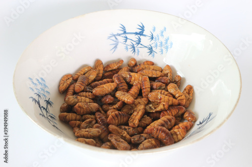 Silkworms fried in a cup on a white background. photo