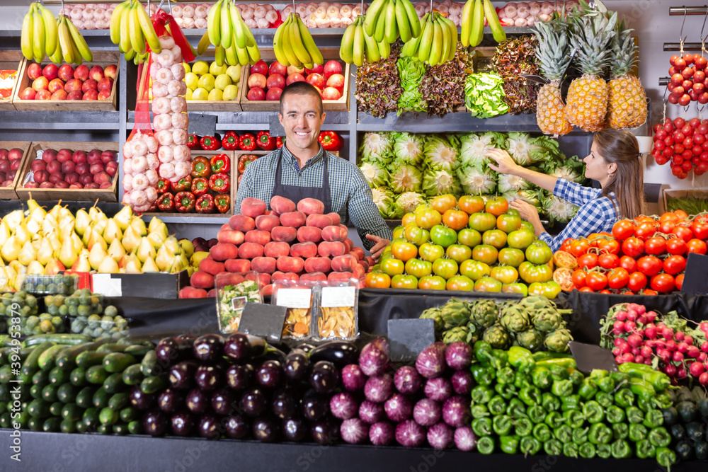 Portrait of male and female young shop assistants working responsibly in fruit and vegetable shop