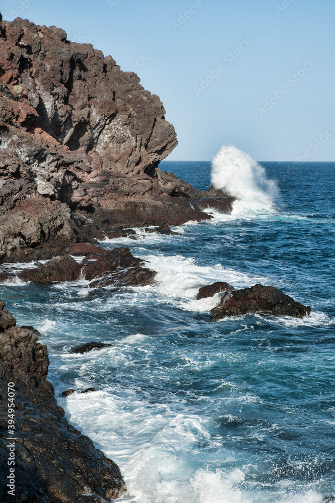 Choppy waves hitting the volcanic rough eastern coast of the island at Montana de la Mar, views of the Atlantic and shore nearby small town known as Puertito de Guimar, Tenerife, Canary Islands, Spain Choppy waves hitting the volcanic rough eastern coast of the island at Montana de la Mar, views of the Atlantic and shore nearby small town known as Puertito de Guimar, Tenerife, Canary Islands, Spain